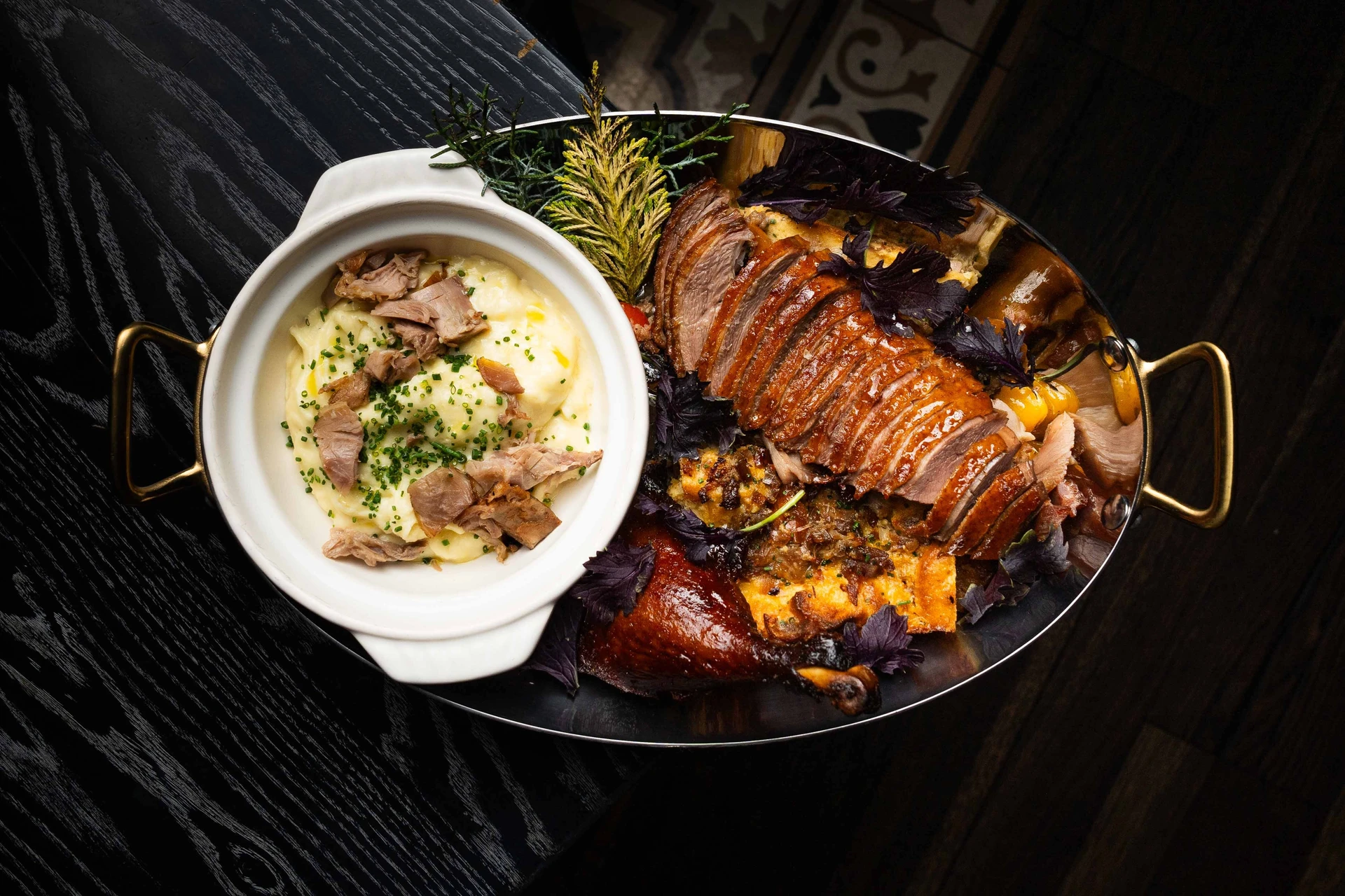 Half a roasted duck and stuffing cast iron plate for Christmas dinner in San Diego at Lionfish.