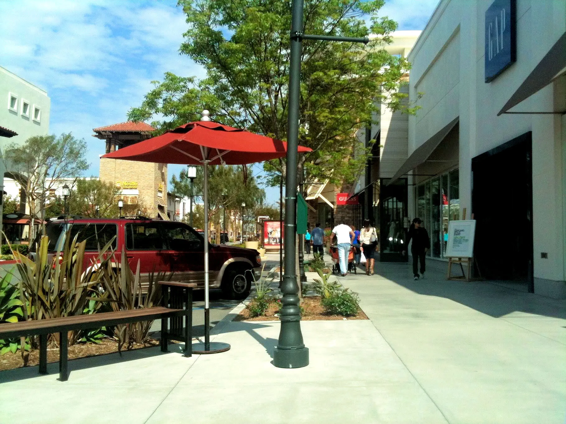 Shoppers walk on the sidewalk in front of stores at Otay Ranch Town Center.