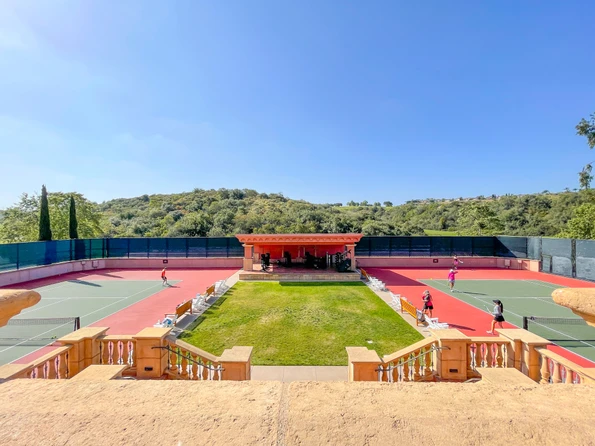 Two tennis courts separated by grass and workout equipment at Fairmont Grand Del Mar.