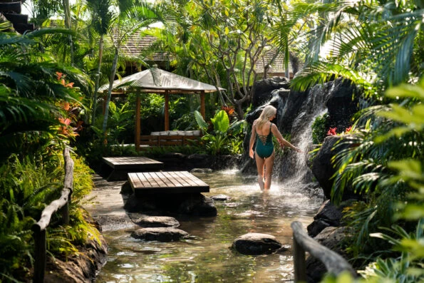 A women puts her hand under a waterfall at the Four Seasons spa.