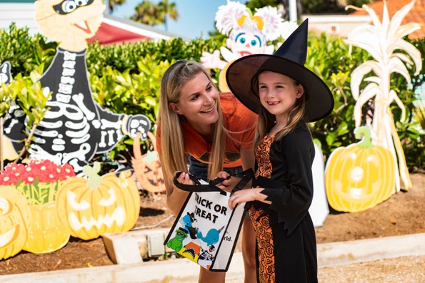 A young girl trick or treats with her mom.