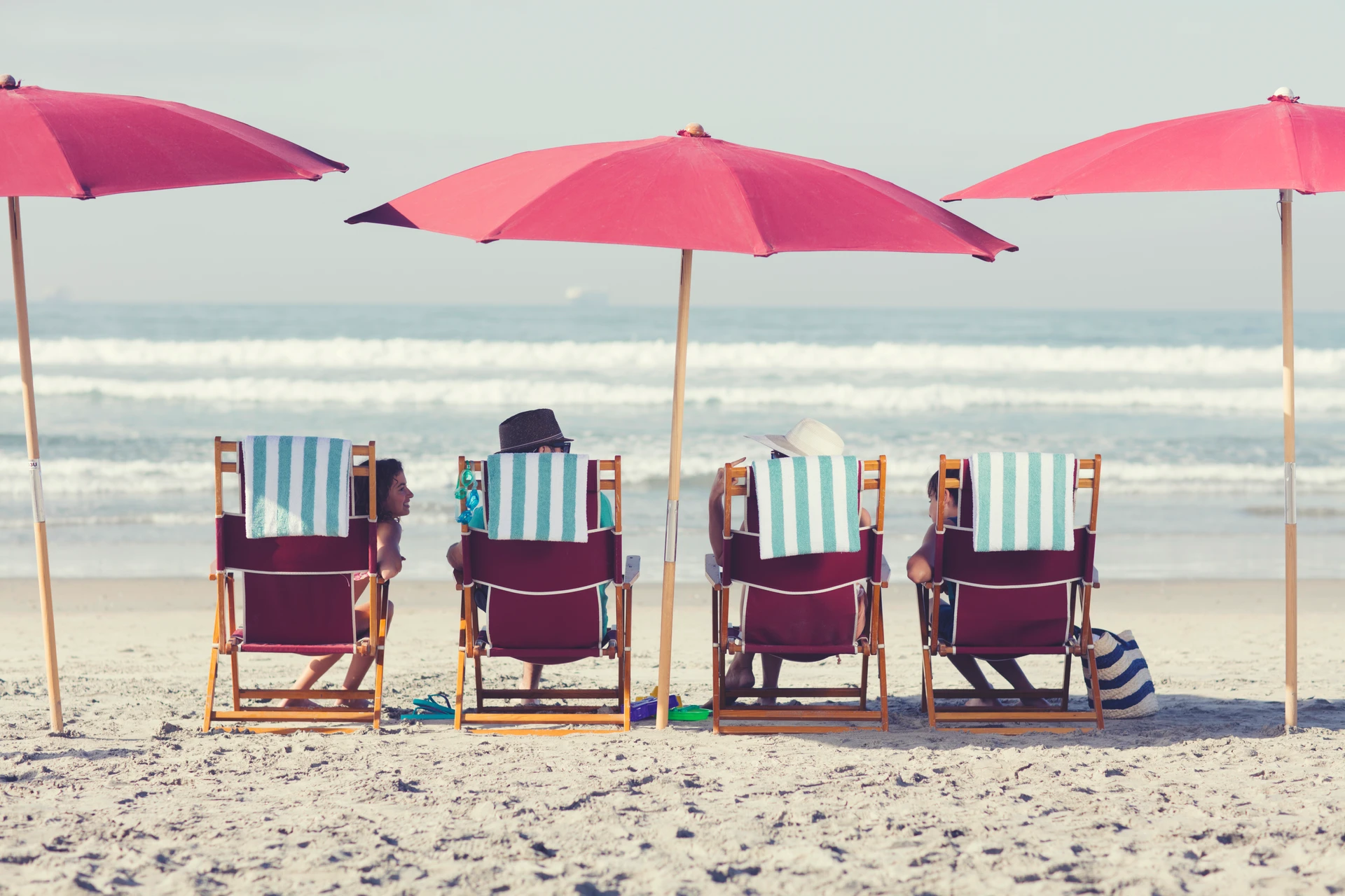 A family sits on Del Beach in the provided beach chairs.