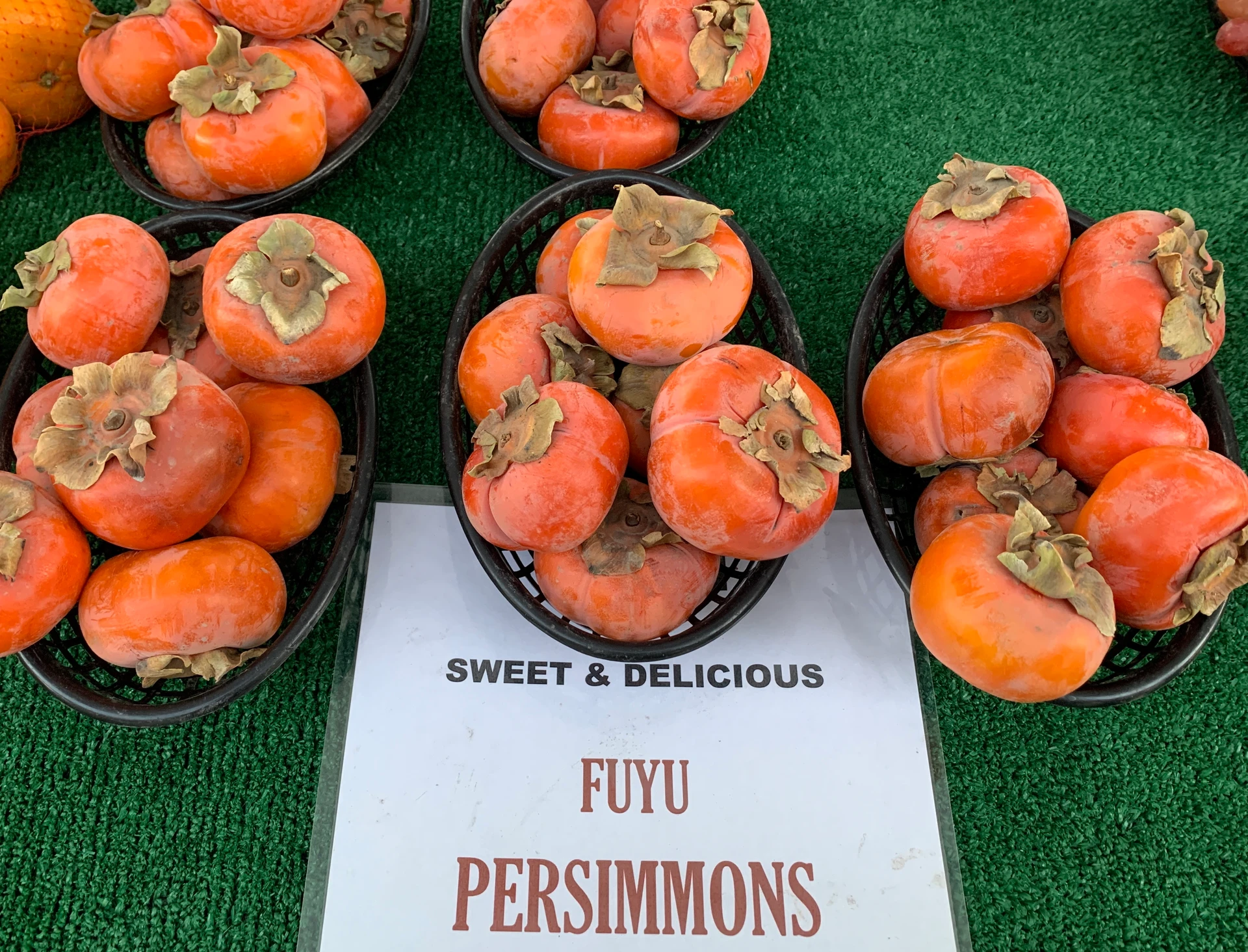 Persimmons in baskets on a table at the Mira Mesa farmer's market in San Diego.