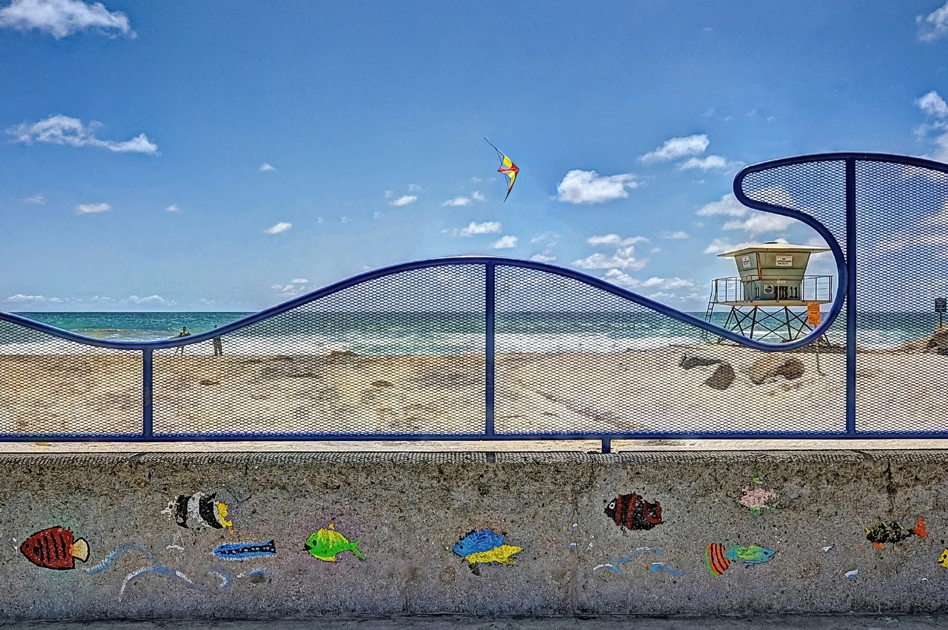 View through a sea-themed colorful fence to the beach.