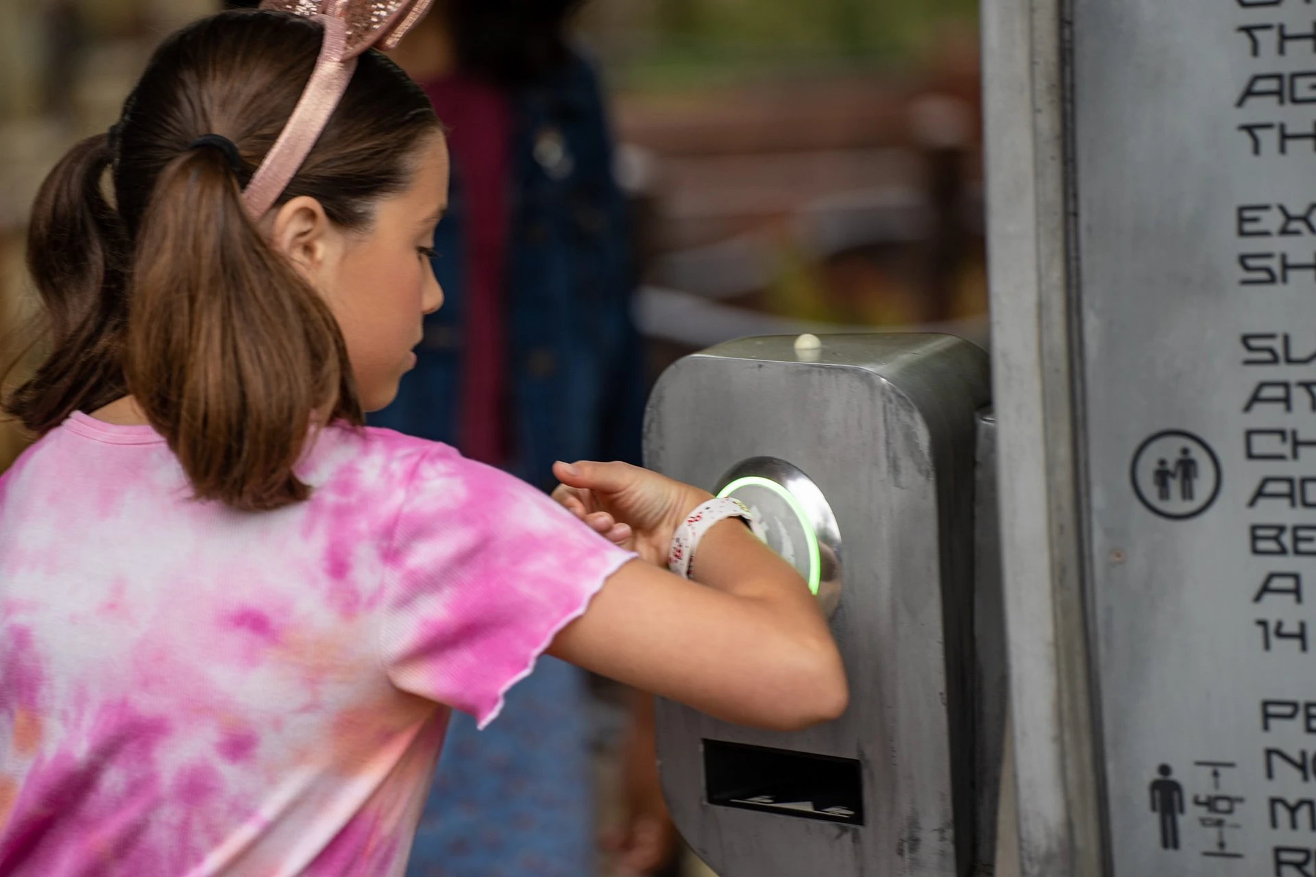 A girl uses her MagicBand to enter a Lightning Lane.