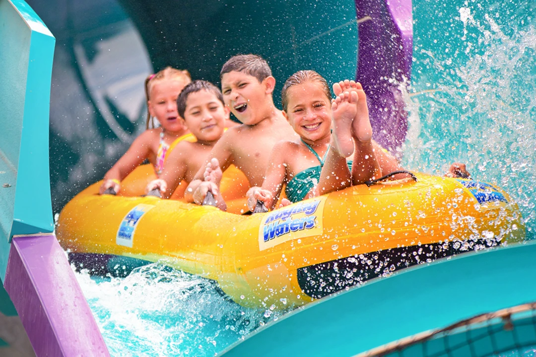 Four young kids in a raft going down a water slide.