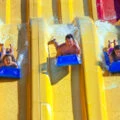 Three people go down a yellow water slide at Raging Waters San Dimas.