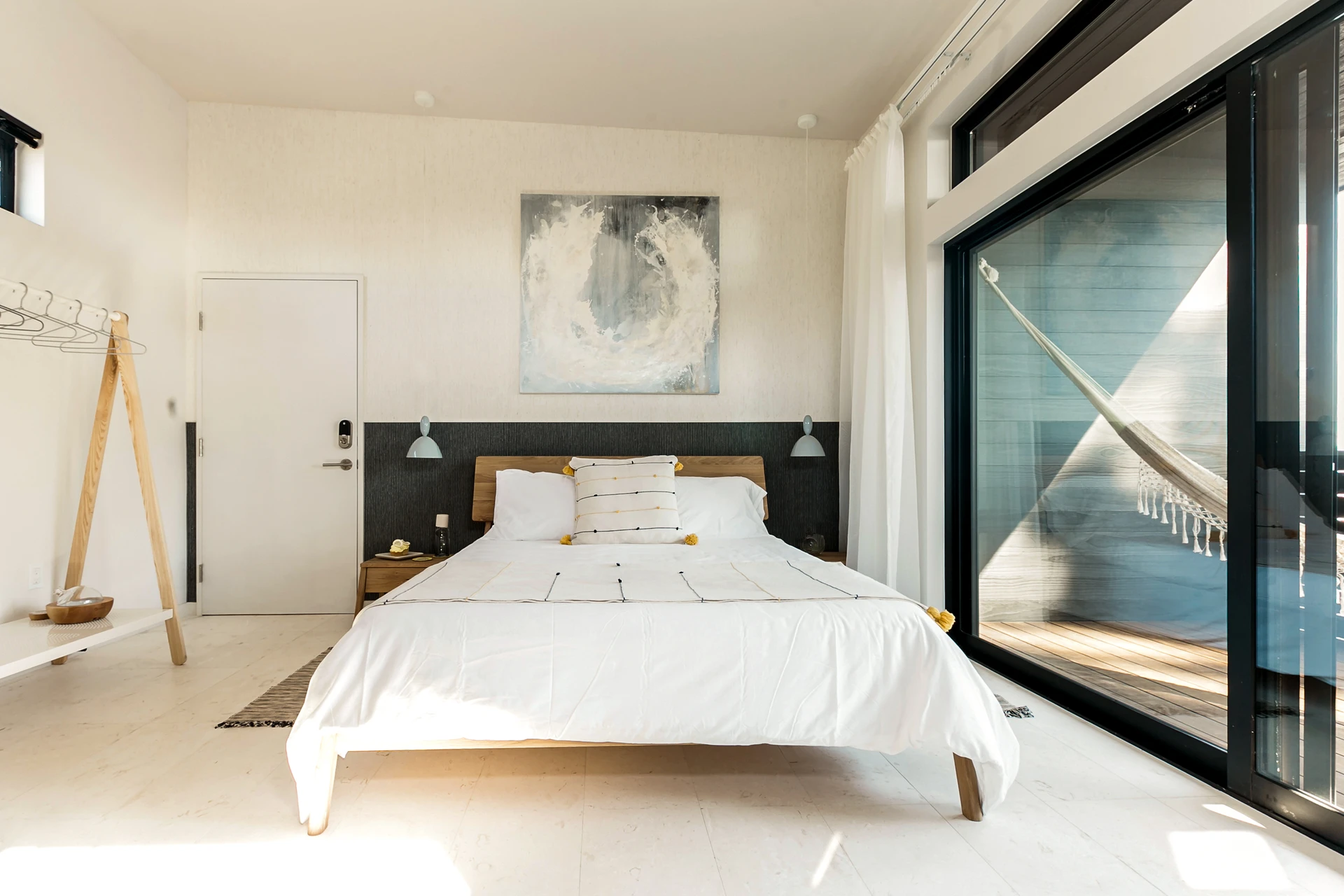 A king bedroom interior with view of hammock on the balcony.