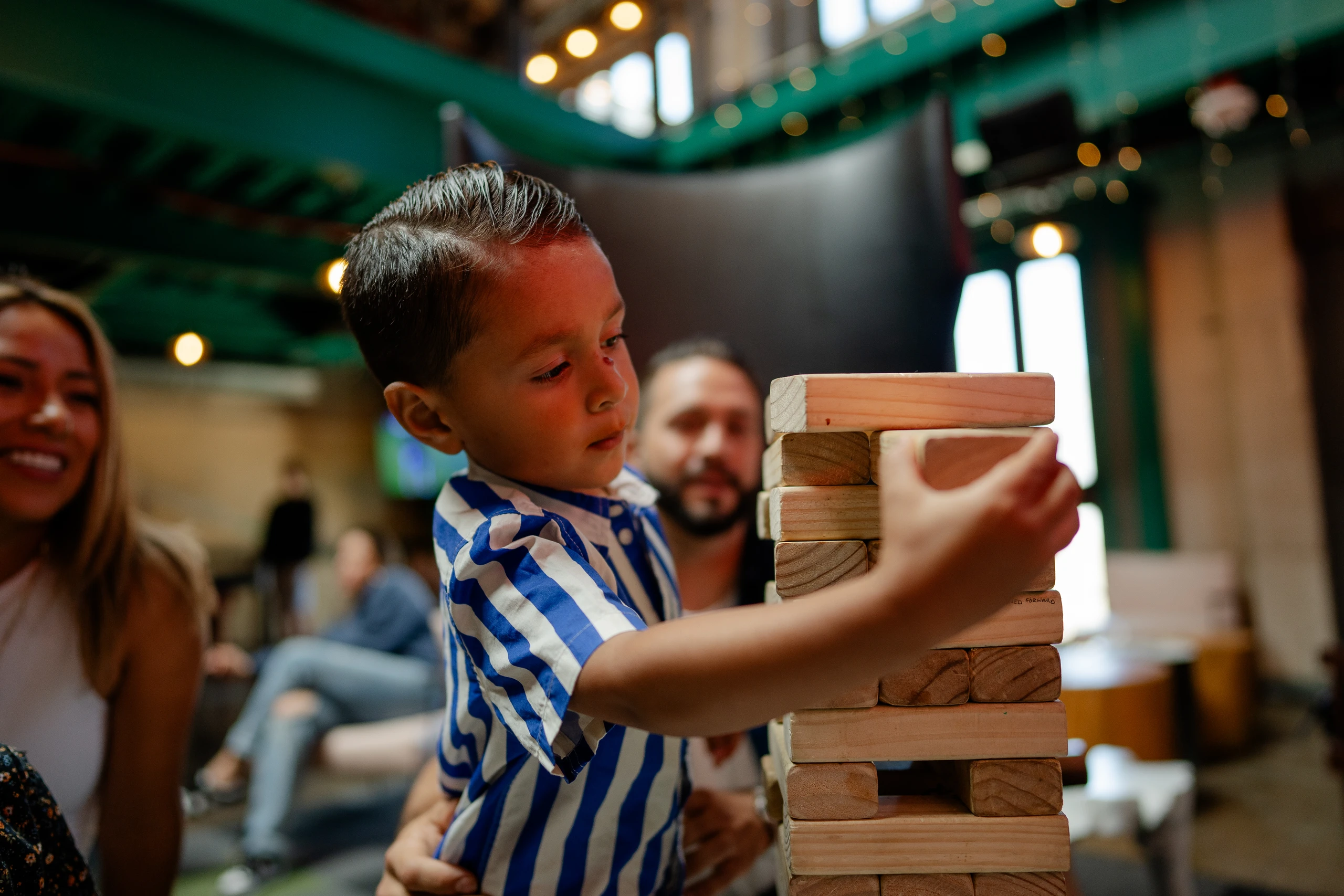A little boy plays Jenga with his family at Punch Bowl Social.