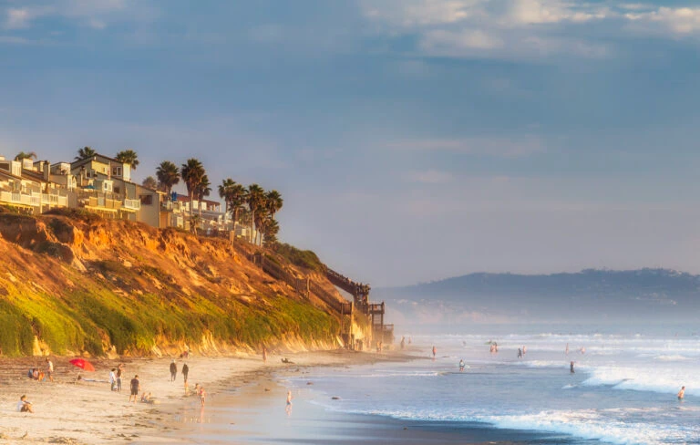 People walk along South Carlsbad State Beach, a fun Carlsbad activity,