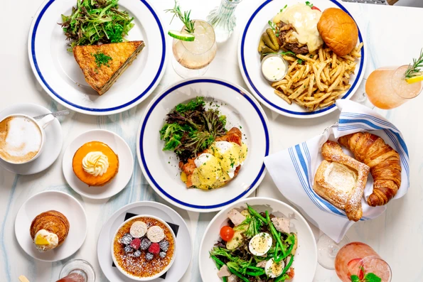 A top-down photo of croissants, salads, burgers, quiche, and more at Little Frenchie, one of the best Coronado restaurants.