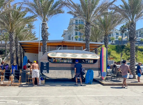 People browse the towels, chairs, and other gear at The Beach Rambler on a sunny day.