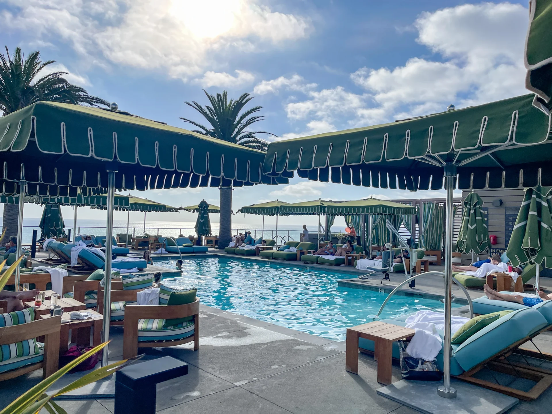 People chill on lounge chairs and in cabanas by the pool near Golden hour.
