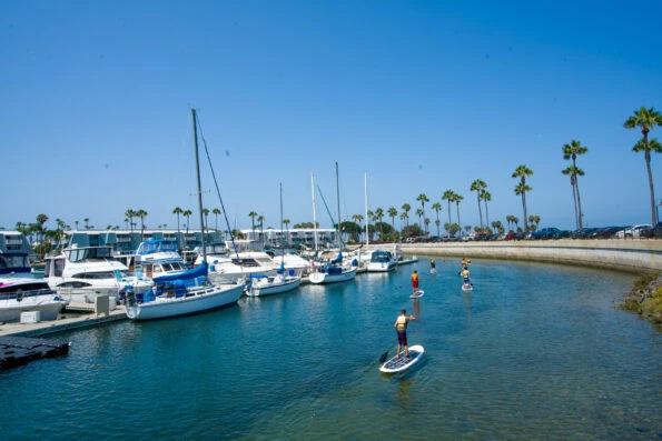 People stand-up paddleboard on a sunny day in Coronado Cays neighborhood.