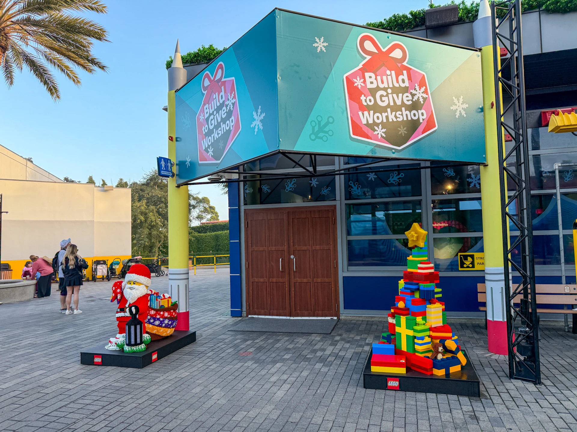 The entrance to the Build to Give Workshop with Christmas LEGO Santa and tree in front.