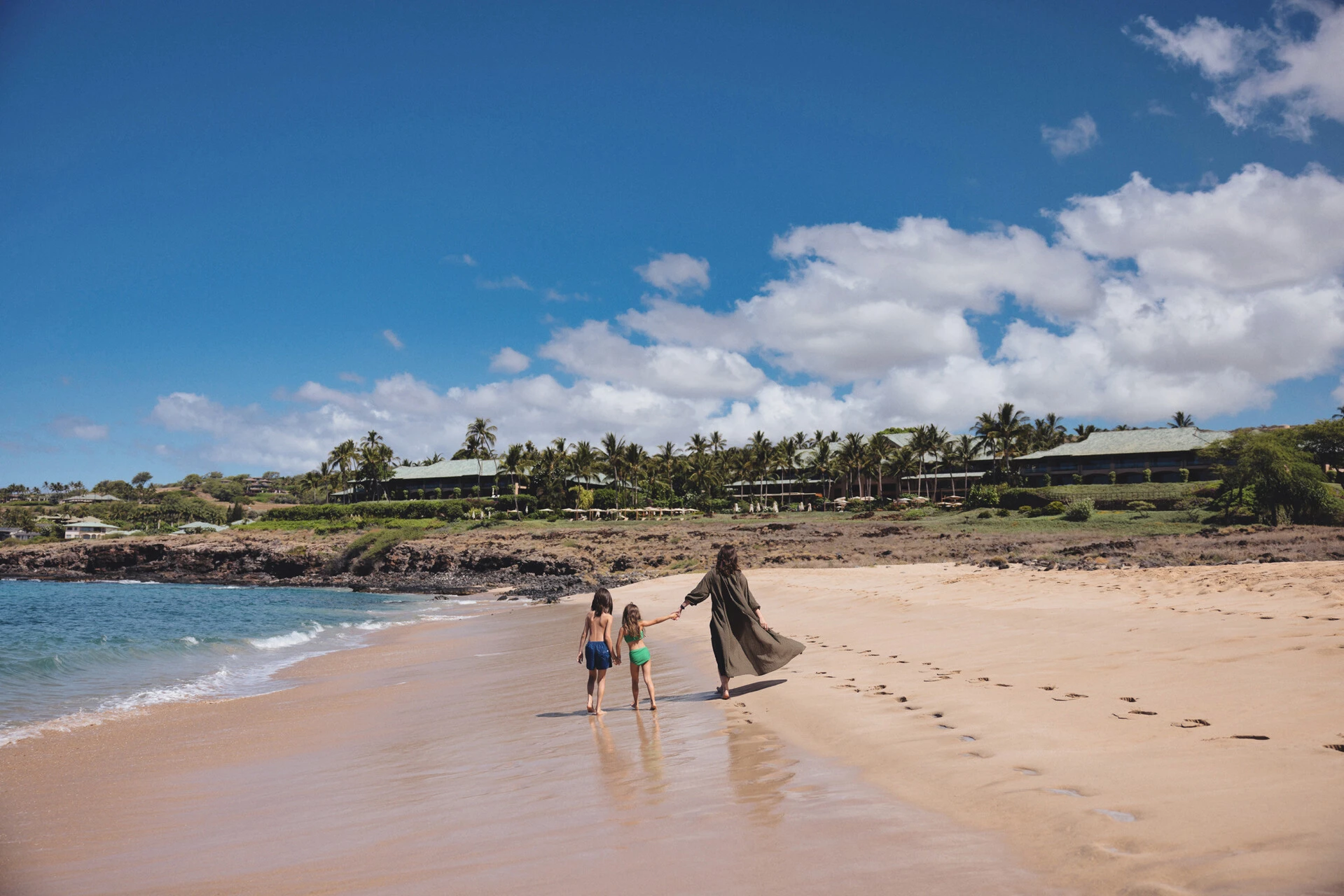 Family walking along the beach near Four Seasons Lanai
