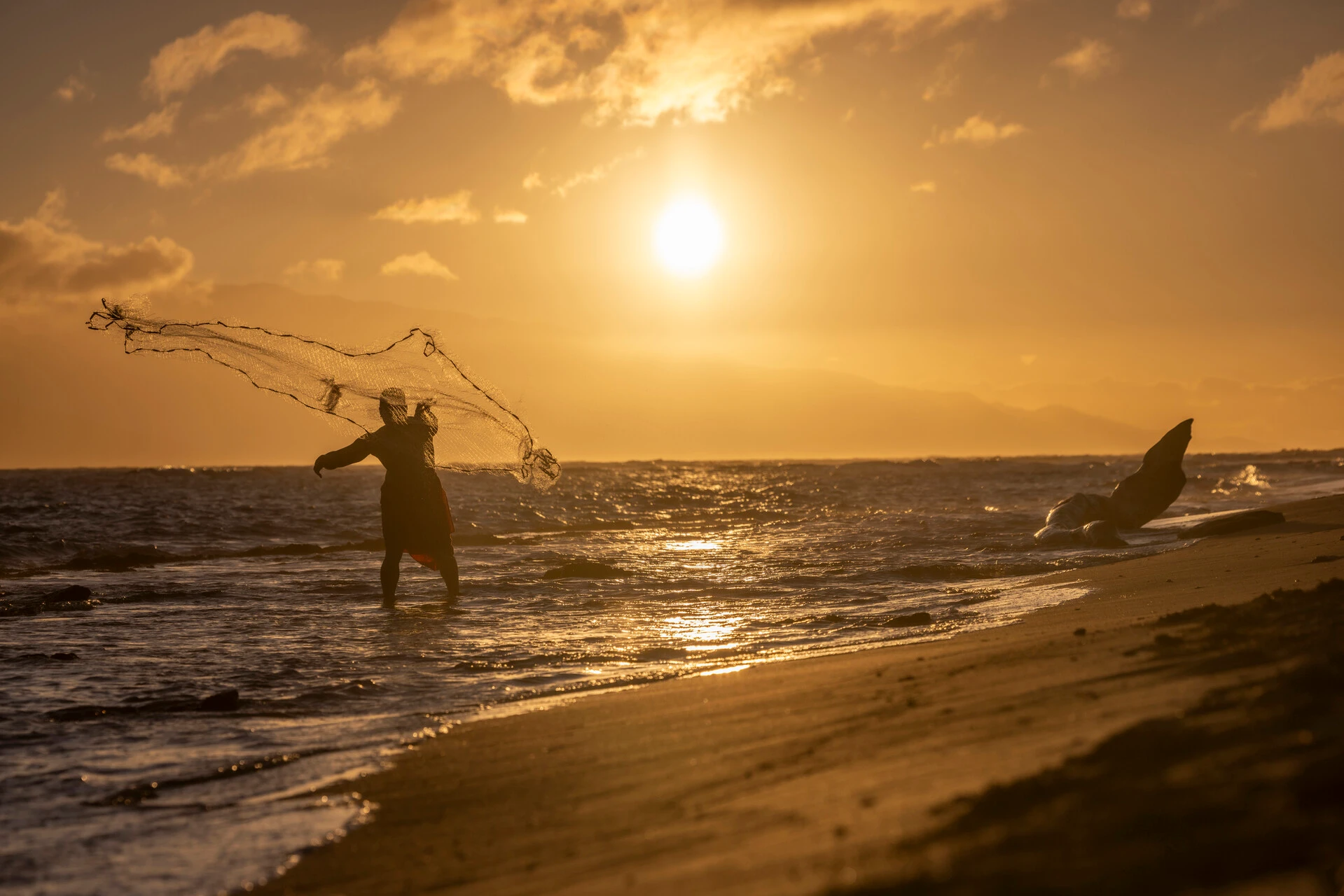 a man fishing during sunset in the beach