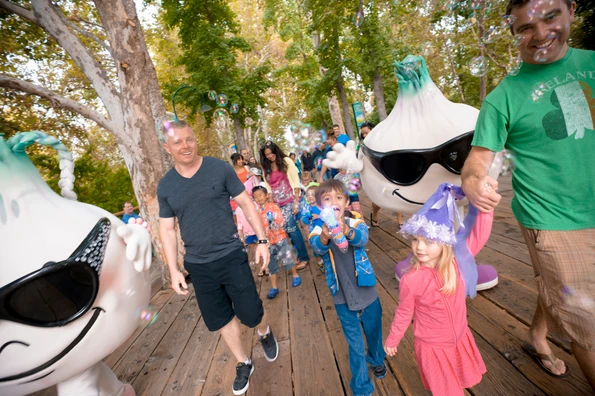 Guests walking across the Sycamore Bridge at Gilroy Gardens with garlic mascots