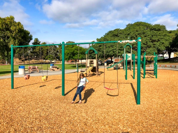 Katie's daughter swings on a plays structure at Kate Sessions Park in San Diego.