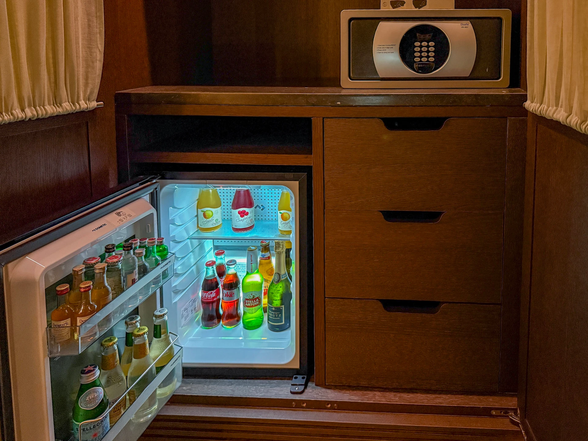 Open minifridge showing soft drinks and bottled juice.