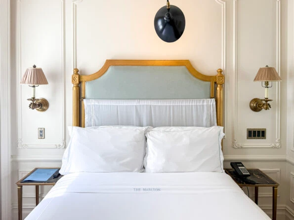 The lovely bed bed with gold headboard and crisp white sheets.