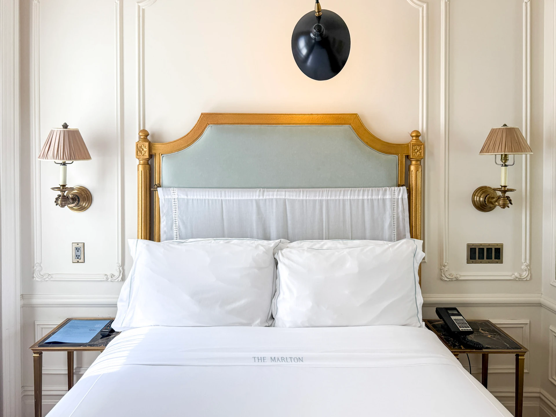 The lovely bed bed with gold headboard and crisp white sheets.