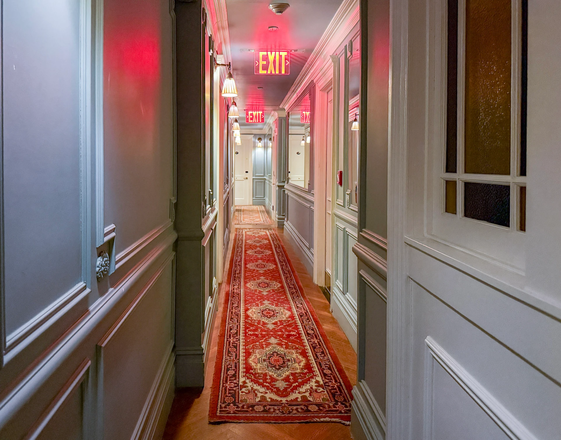 An Oriental carpet spans the narrow white and blue paneled hallways between rooms.