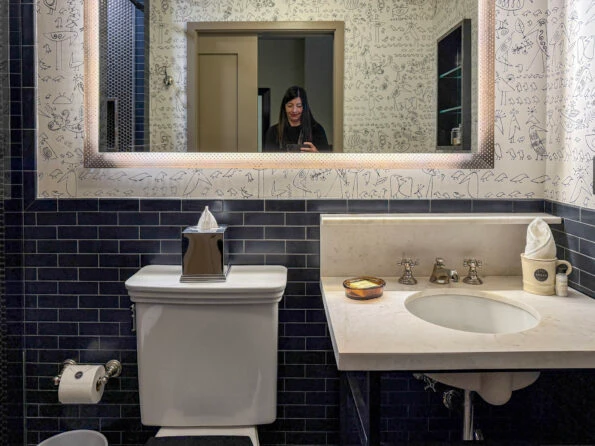 Soho Grand bathroom with bird wallpaper, mirror, sink area.