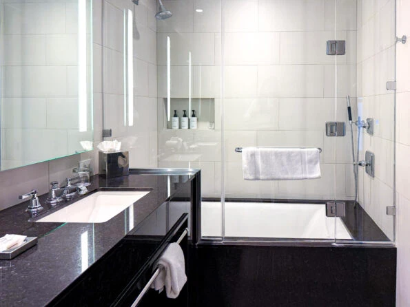 Black marble tub/shower combo with white tile walls in my bathroom at The St. Anthony Hotel in San Antonio.