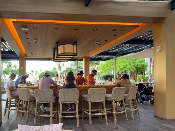 Guest sit around the bar while bartenders prepare drinks.