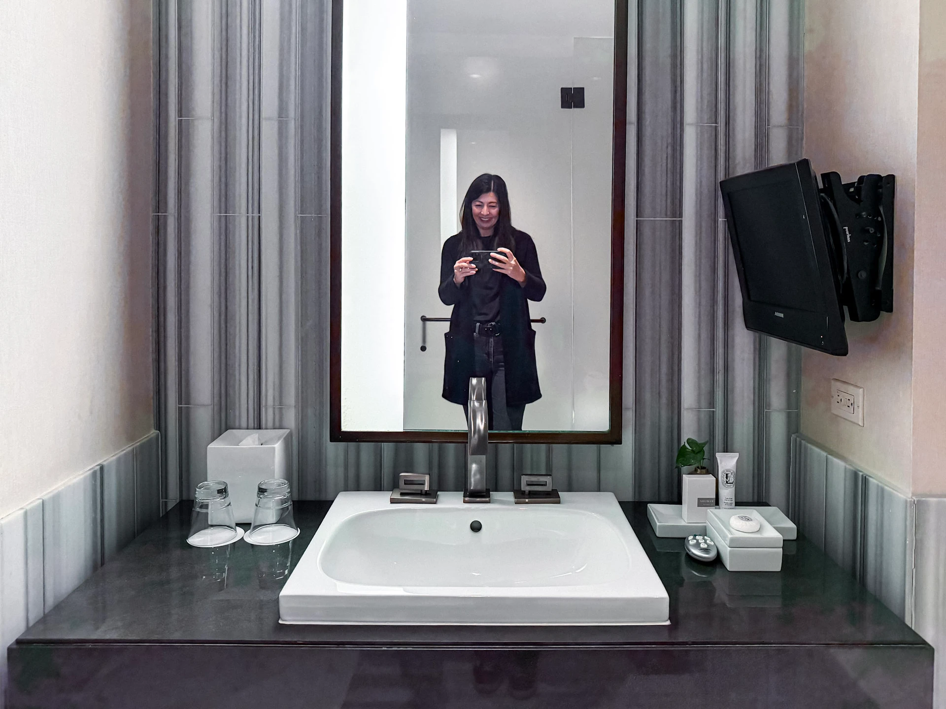 The bathroom vanity with me shown in the mirror.