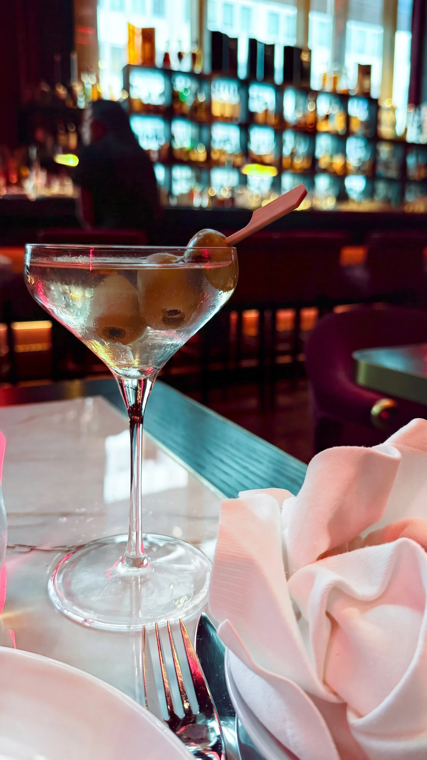 A martini with olives sits on a table at CUT.