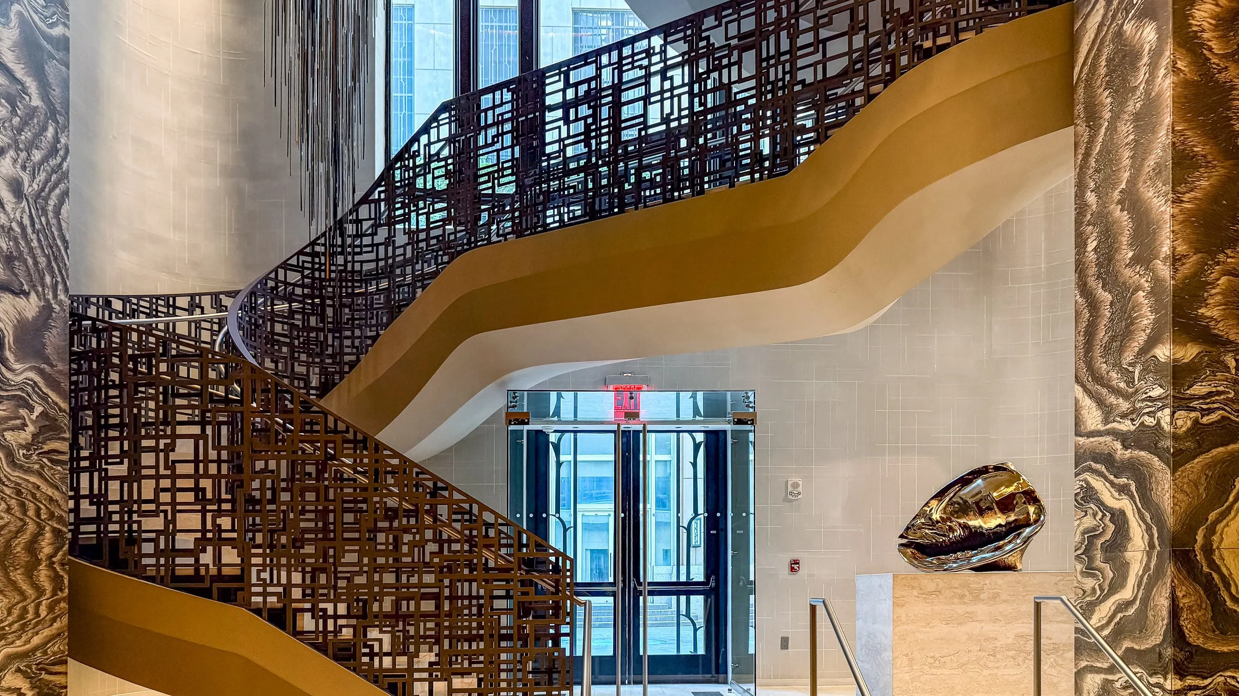 The staircase at Four Seasons Hotel New York Downtown, with marble walls and a steel railing.