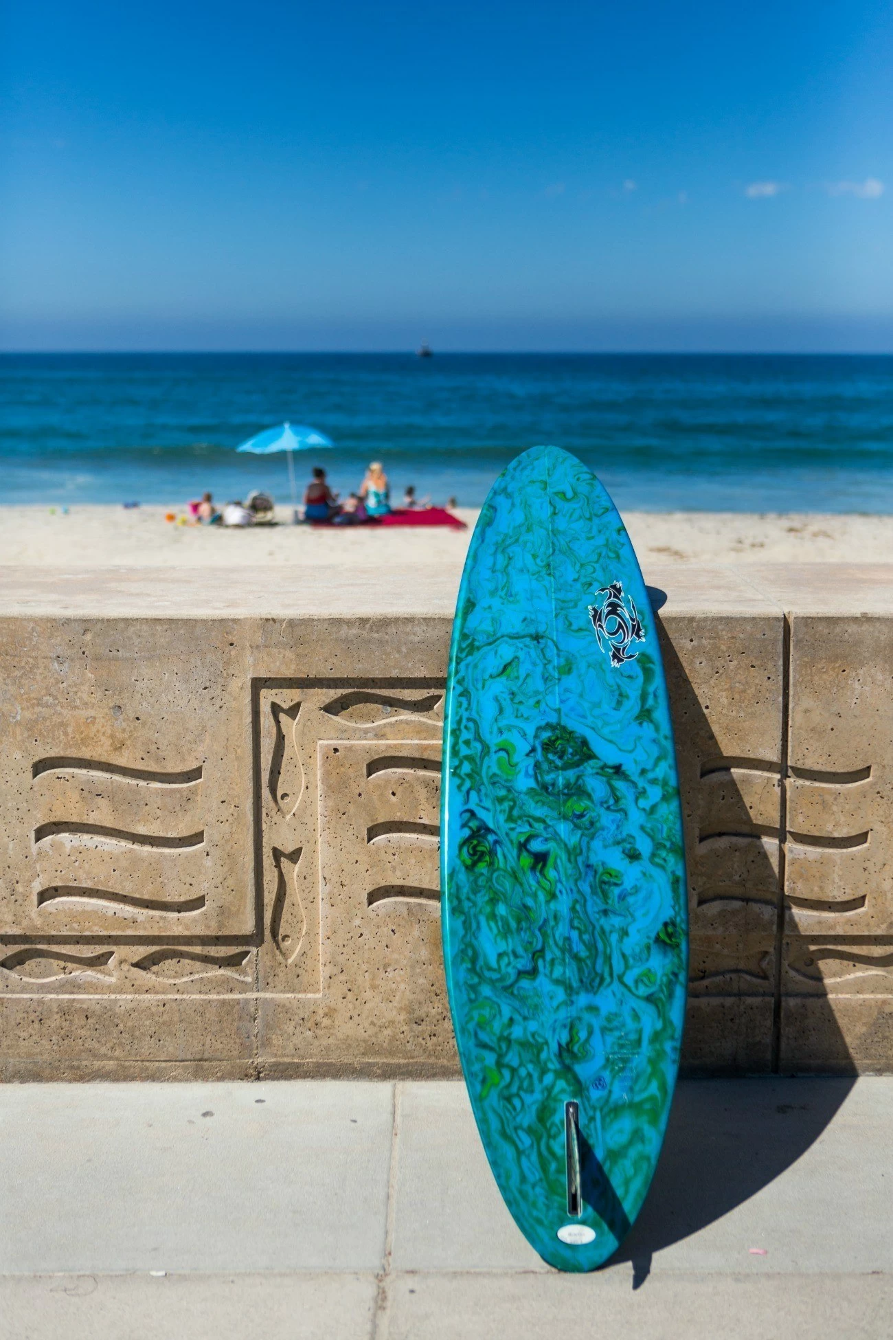 A surfboard leans against a wall along the beach in Carlsbad Calfornia.