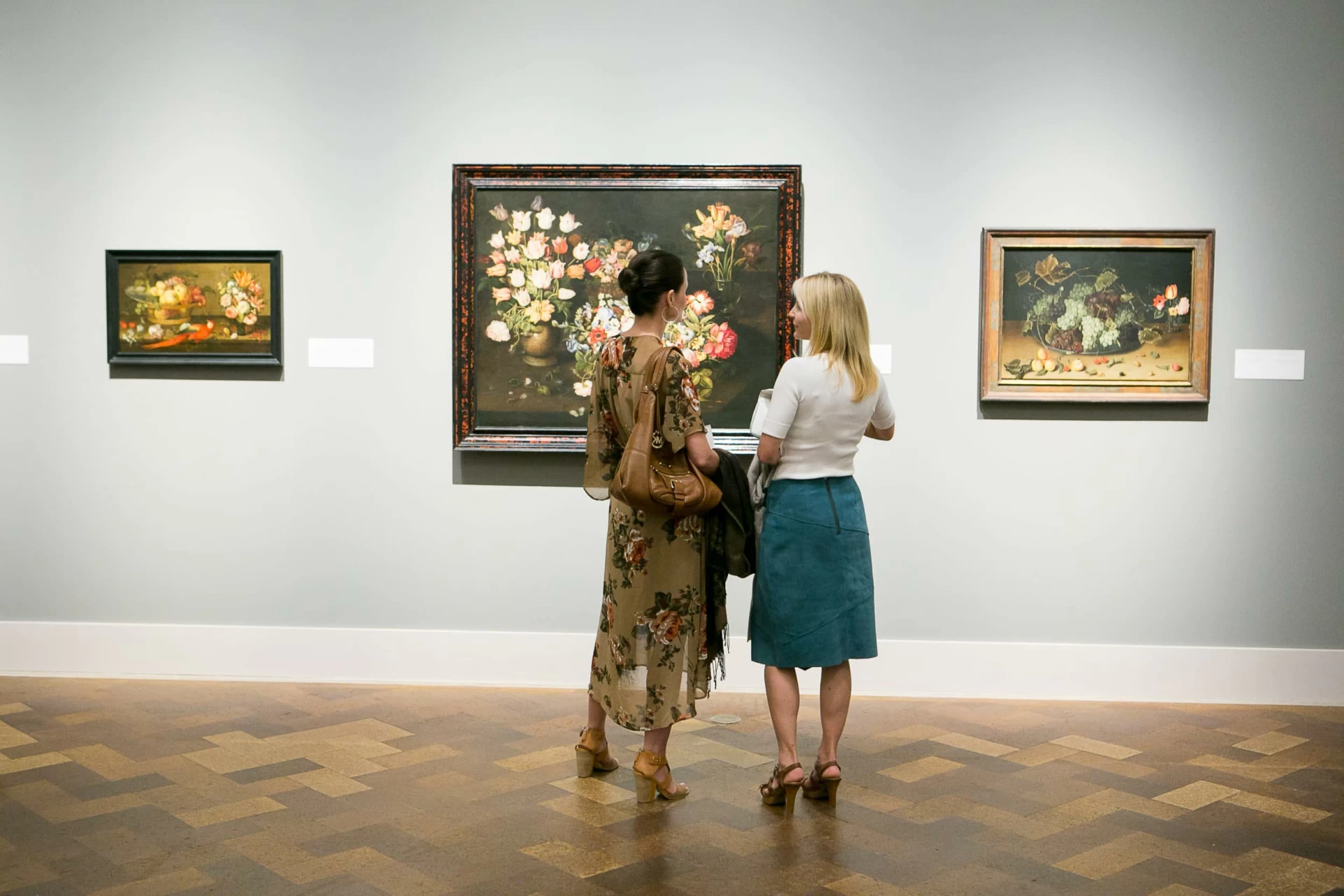 Two women stand in front of a painting at San Diego Museum of Art