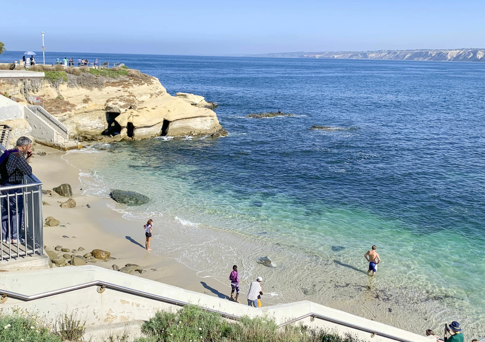 People wading into the water at La Jolla Cove on an October morning.