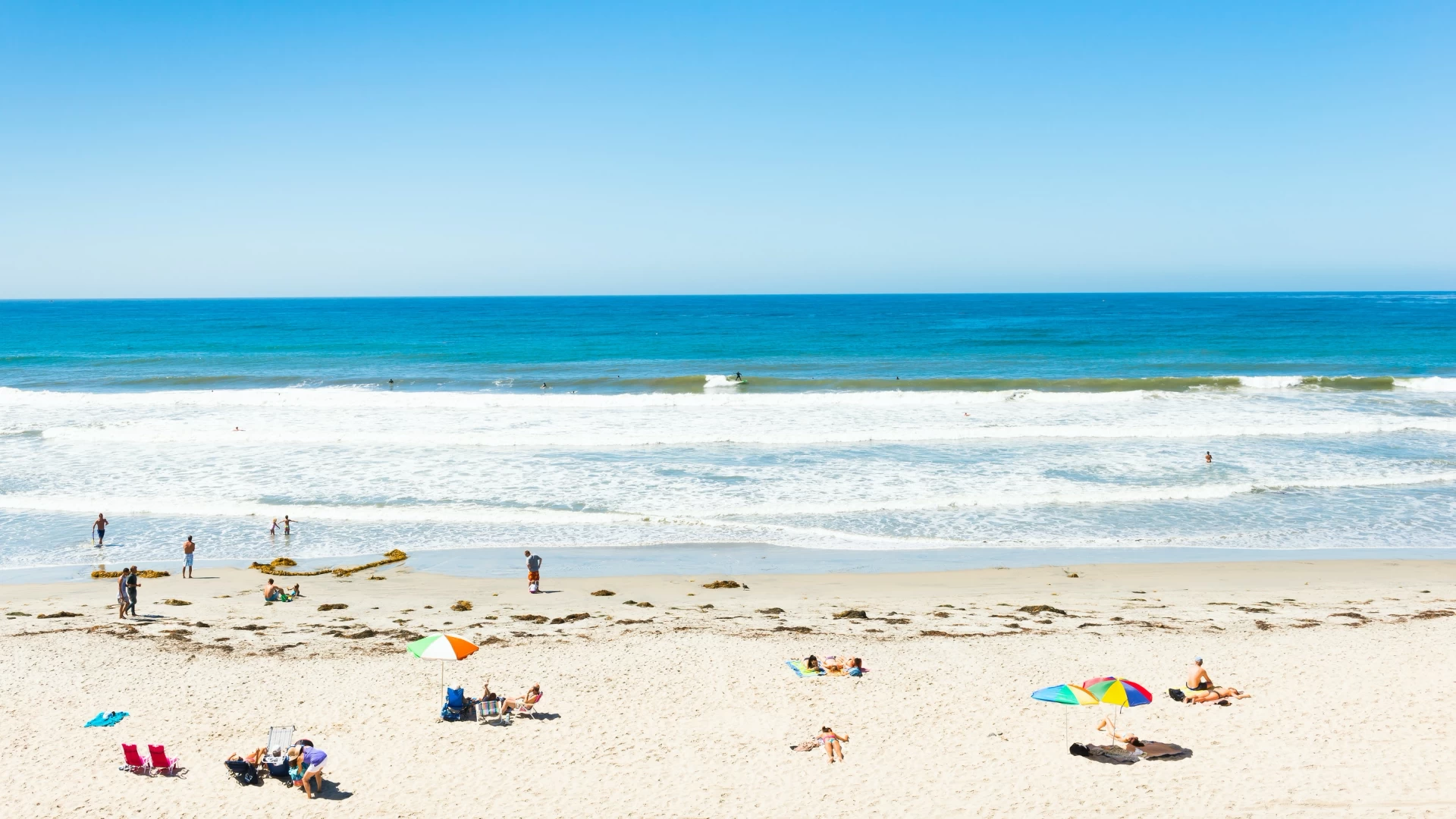 People swim and sunbathe at the beach on a sunny day, one of the most popular things to do in San Diego with kids.