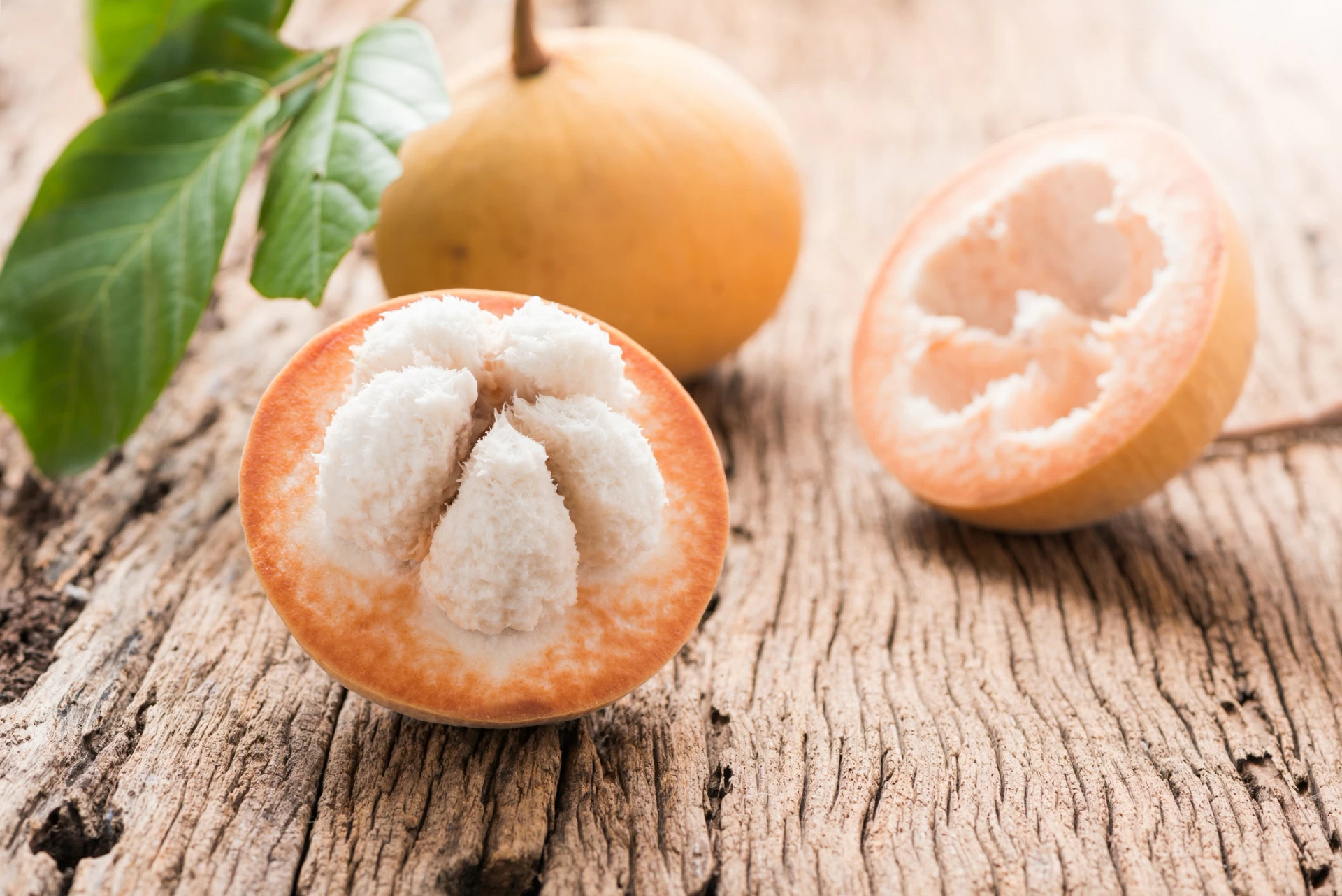 Exotic santol fruit cut in half on a piece of wood.