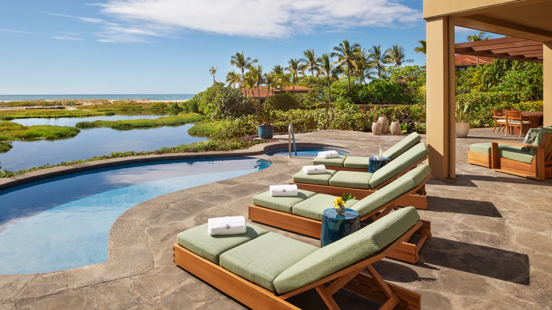 Lounge chairs overlooking a small pool and pond out to the ocean.